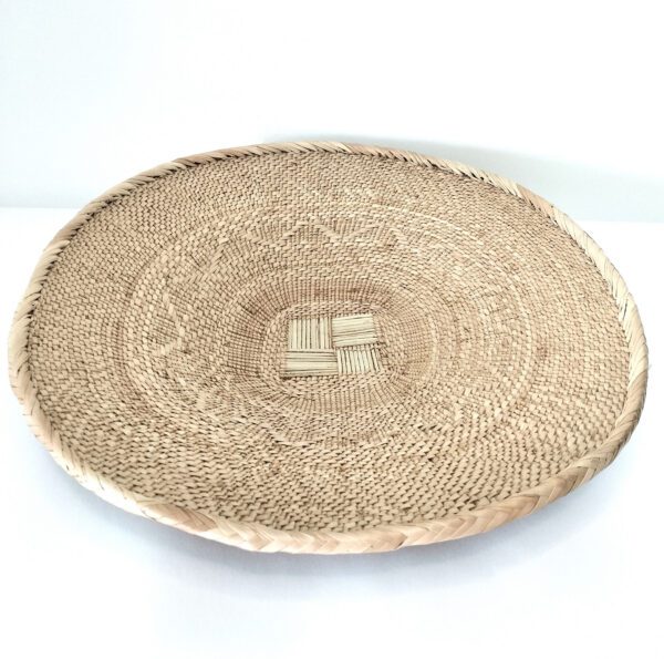 Prato Binga artesanal em folha palma na sua cor natural, 40cm. Para composições decorativas de parede ou simplesmente para acomodar objetos, frutos secos, etc. Está sobre um fundo branco.