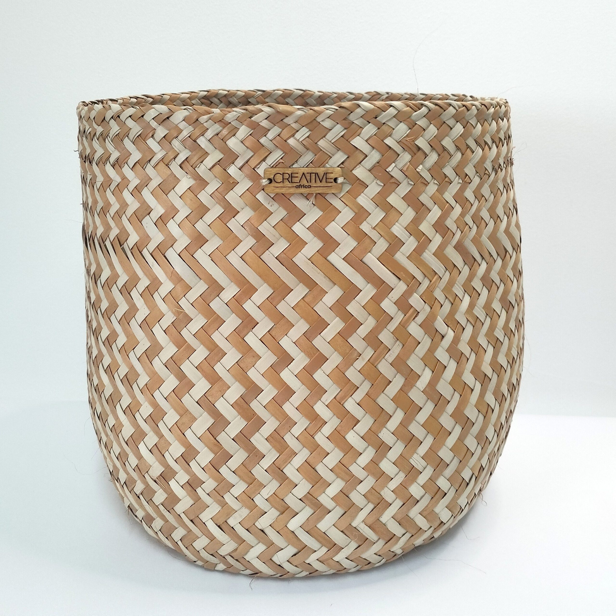 Cesta artesanal multiusos natural e laranja média em folha de palma. Padrão em zigue-zague. Está exposta sobre um fundo branco.