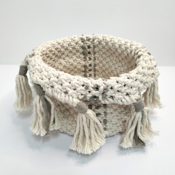 Cesto multiusos em macramé, está sobre um fundo branco.