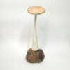 Cogumelo decorativo de cerâmica artesanal com base em pedra natural. Está exposto sobre um fundo branco.