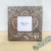 Moldura artesanal em madeira de manga pirogravada para fotografia de 10x10cm. Está sobre uma prateleira com um raminho de alfazema ao lado.