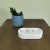 Castiçal para 2 vela tealight em resina ecológica em tons de areia. Está sobre madeira com uma vaso de cerâmica azul com suculenta atrás.