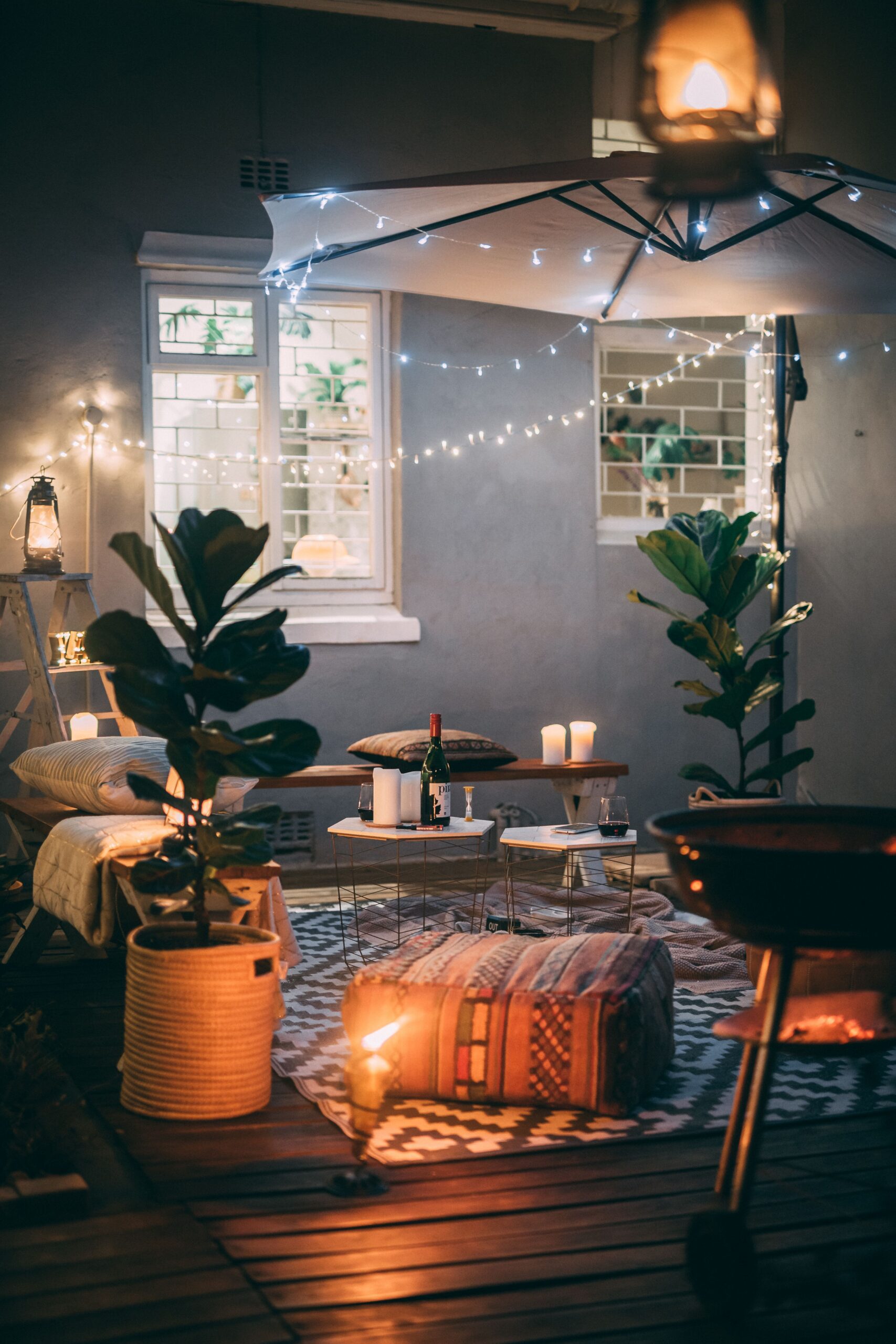 Ambiente de terraço à noite, com plantas, luzes, mesas de apoio e bancos, mantas,... Materiais naturais num ambiente acolhedor.