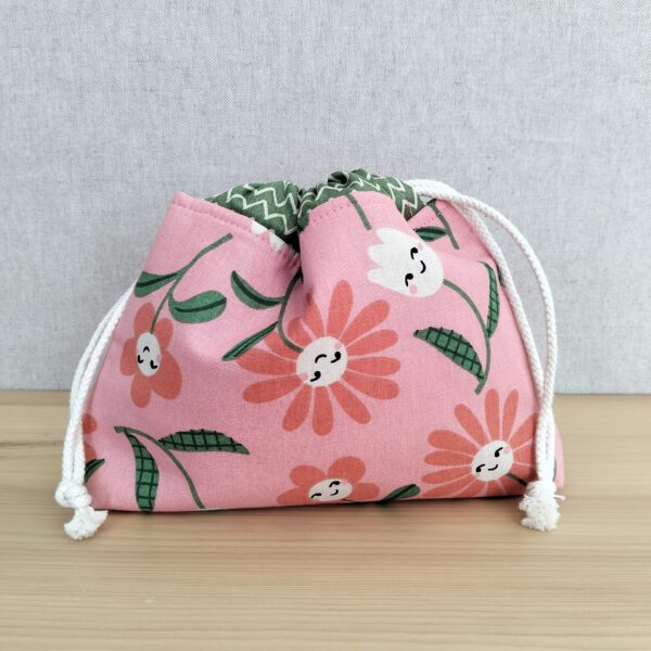 Bolsa rosa em tecido de algodão com cordão ajustável e padrão floral.