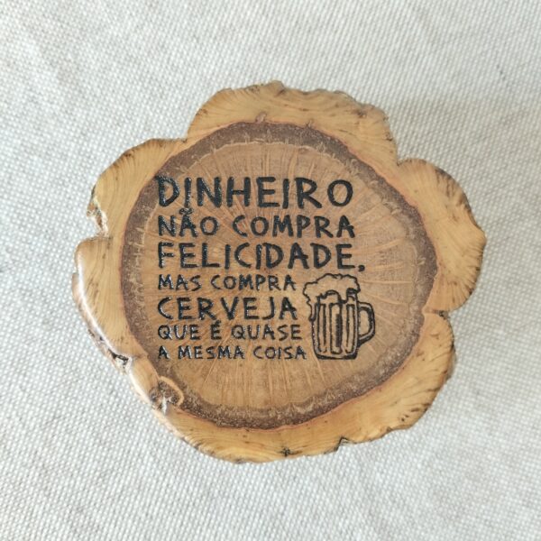 Abre-cápsulas artesanal em madeira de sobreiro. è uma rodela de sobreiro pirogravada em cima com a frase "Dinheiro não compra felicidade, mas compra cerveja que é quase a mesma coisa."