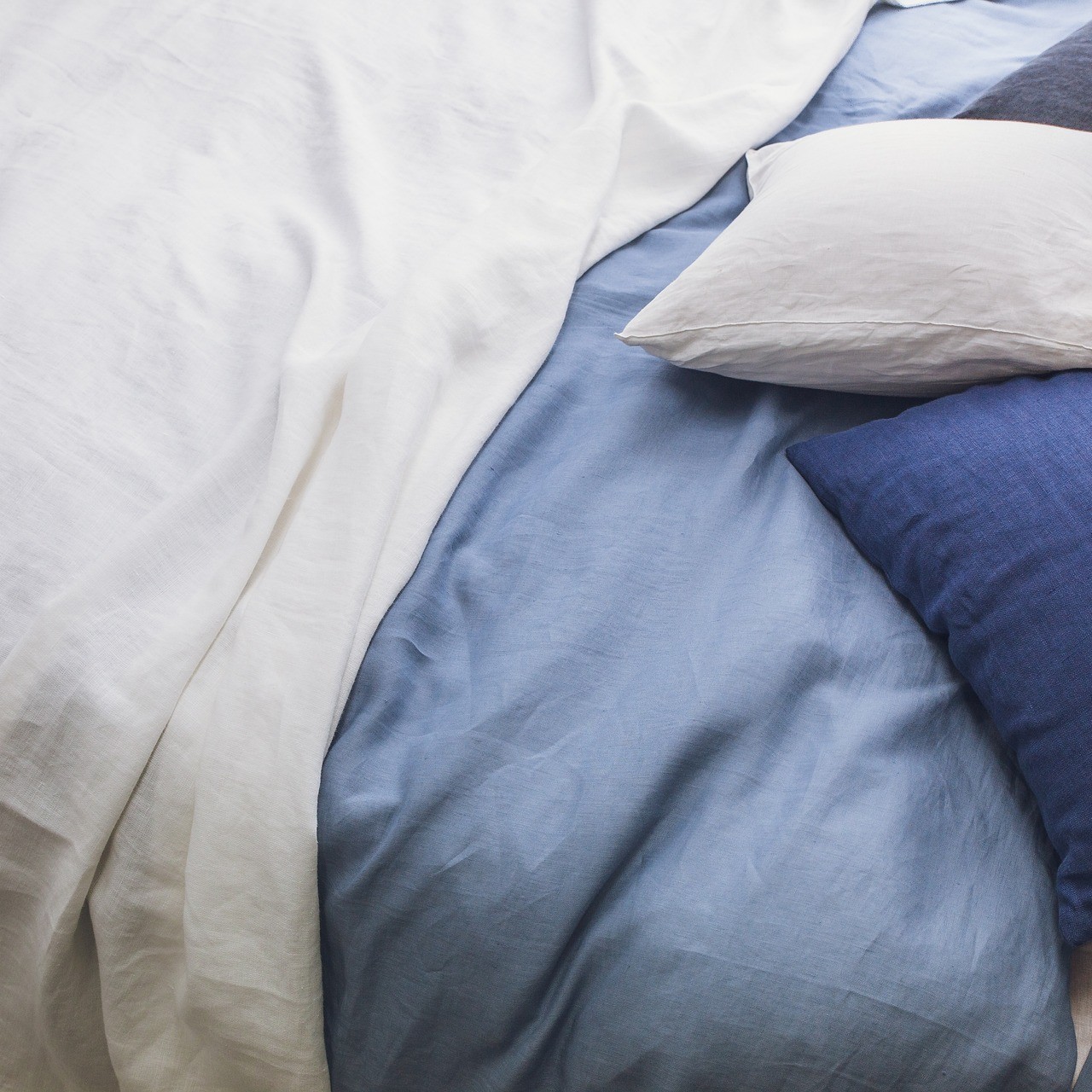 Close-up de roupa de cama em linho em tons de branco e azul.